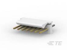 Ein weißer Kunststoffstecker mit mehreren goldfarbenen Metallstiften, die herausragen. Der Stecker liegt auf einer hellen Oberfläche.