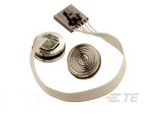 Ein elektrisches Bauteil mit flachem Kabel und zwei runden Sensoren. Es scheint für technische Anwendungen oder Reparaturen gedacht zu sein.