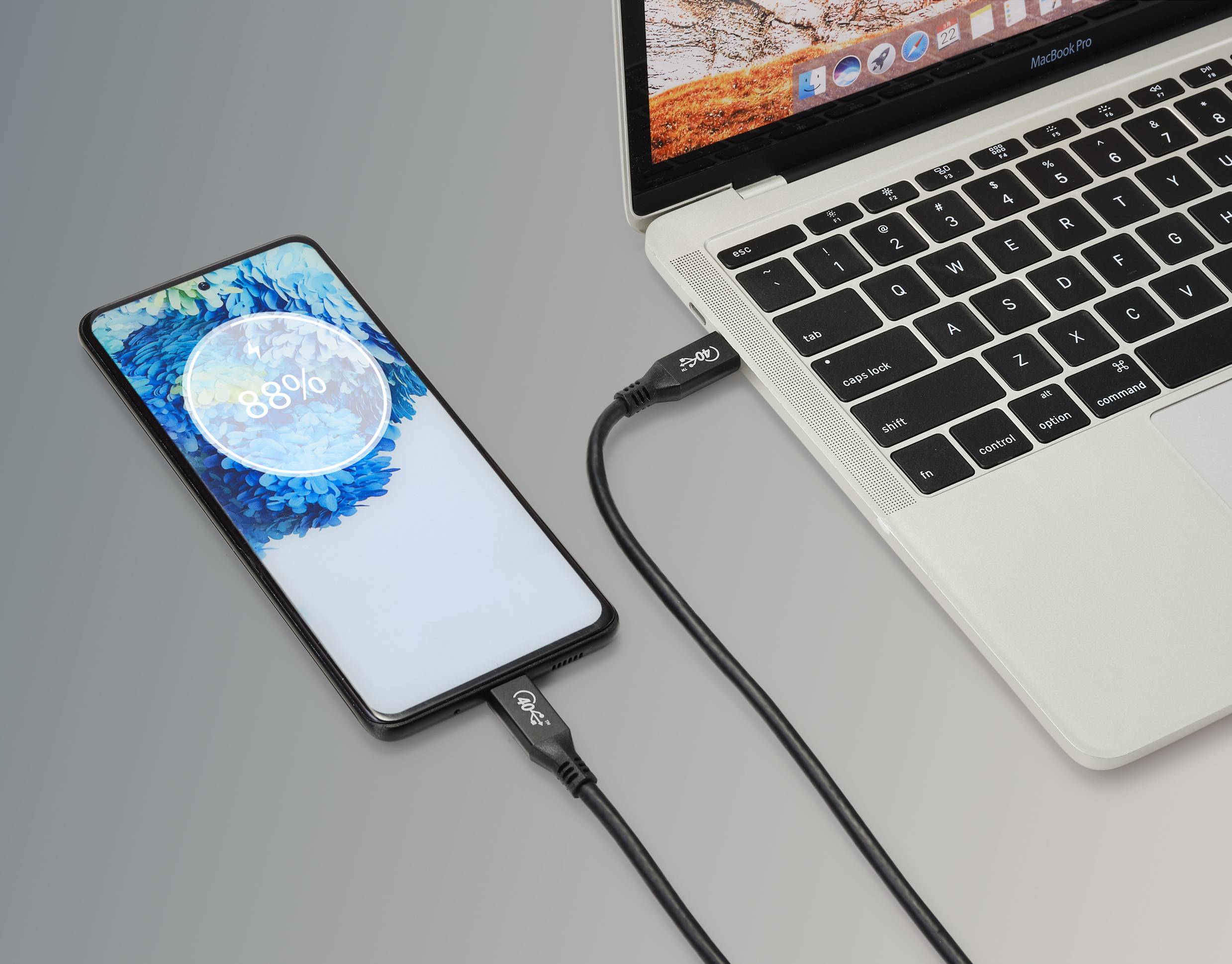 Smartphone geladen von Laptop über USB-Kabel, zeigt 88% geladen an. Bildschirm zeigt Ladeanimation. Laptop mit offenem Bildschirm.