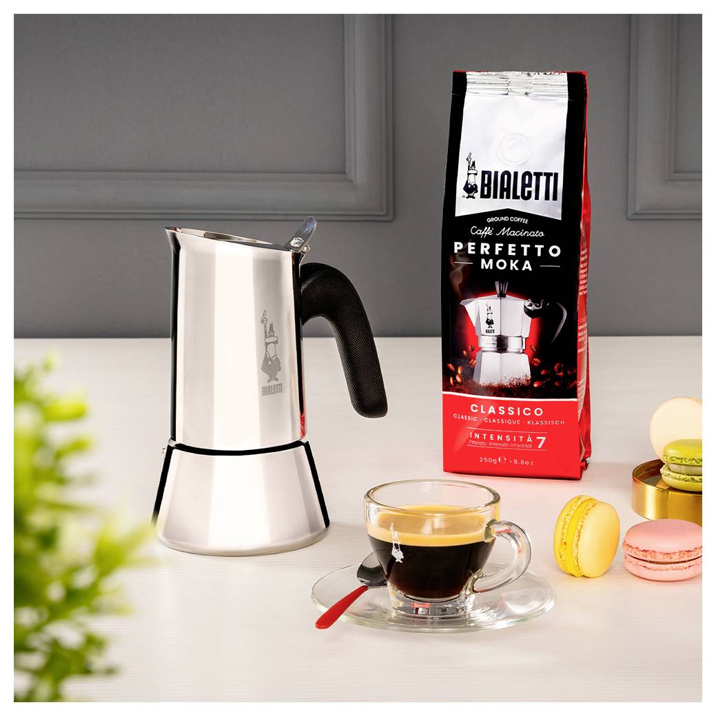 Ein Espressokocher auf dem Herd neben einer Packung Kaffee mit der Aufschrift 