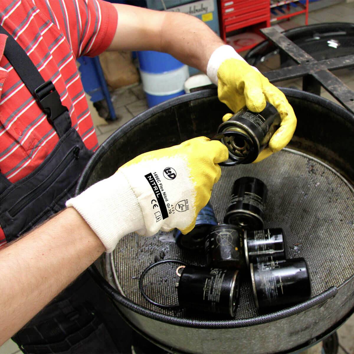 Person sortiert schwarze Filter in einem Behälter. Die Person trägt Handschuhe.