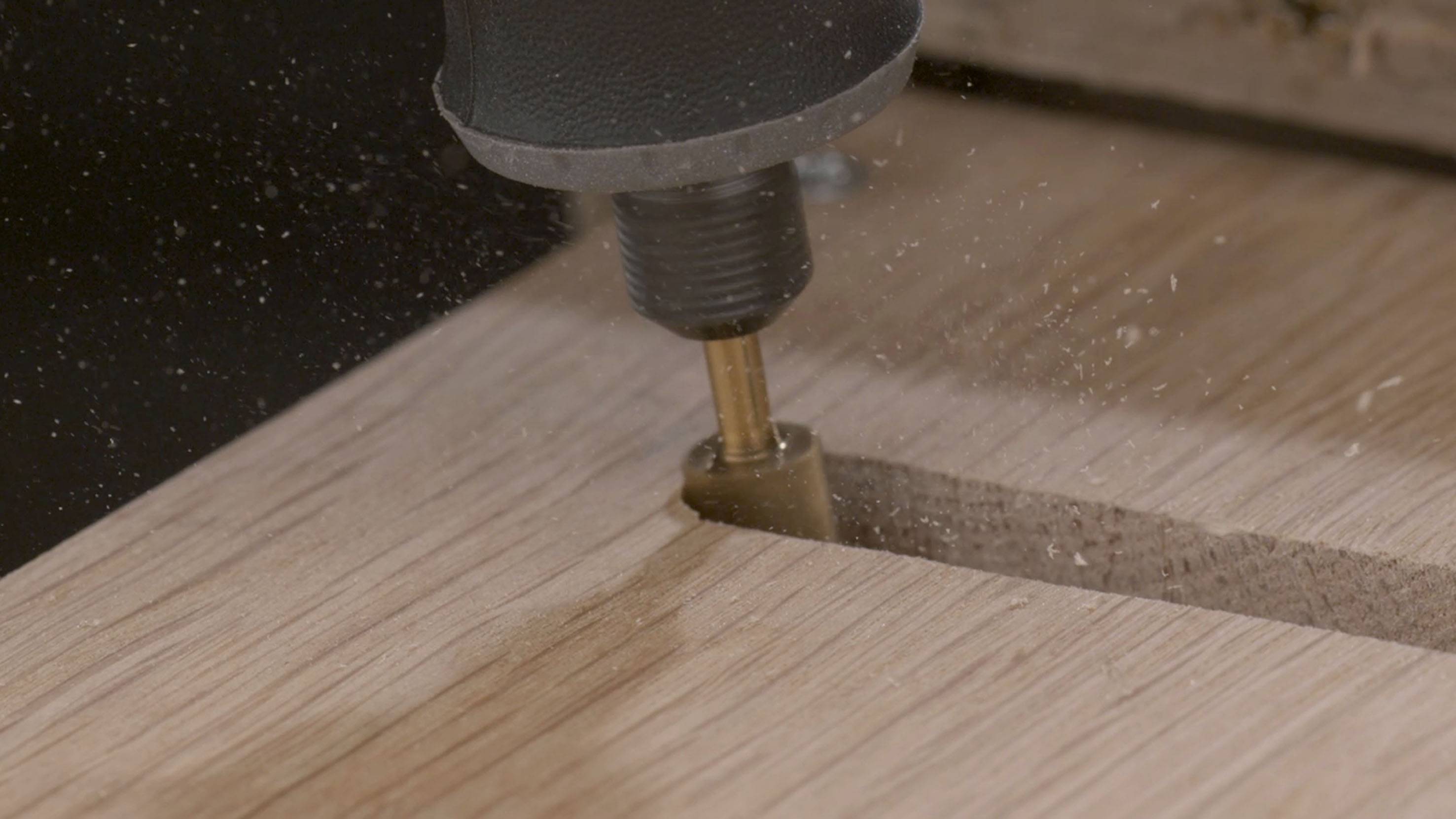 Eine Fräse bearbeitet eine Holzfläche, dabei entstehen Holzspäne.