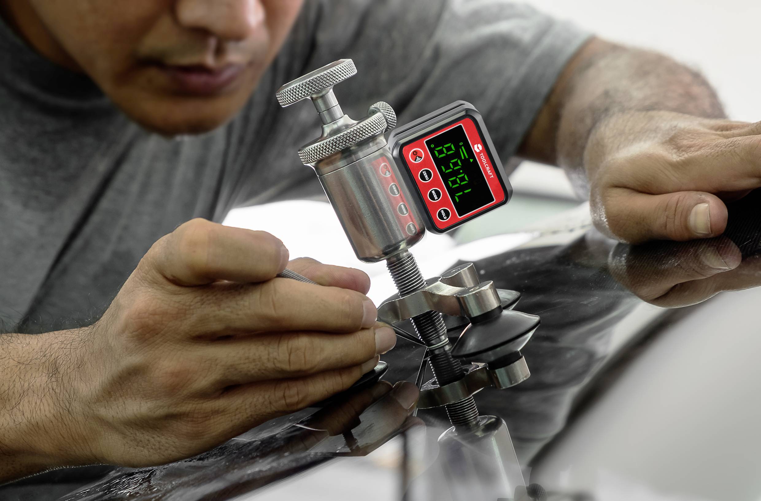 Eine Person arbeitet mit einem digitalen Messgerät an einem Autoteil, möglicherweise zur Überprüfung oder Reparatur.