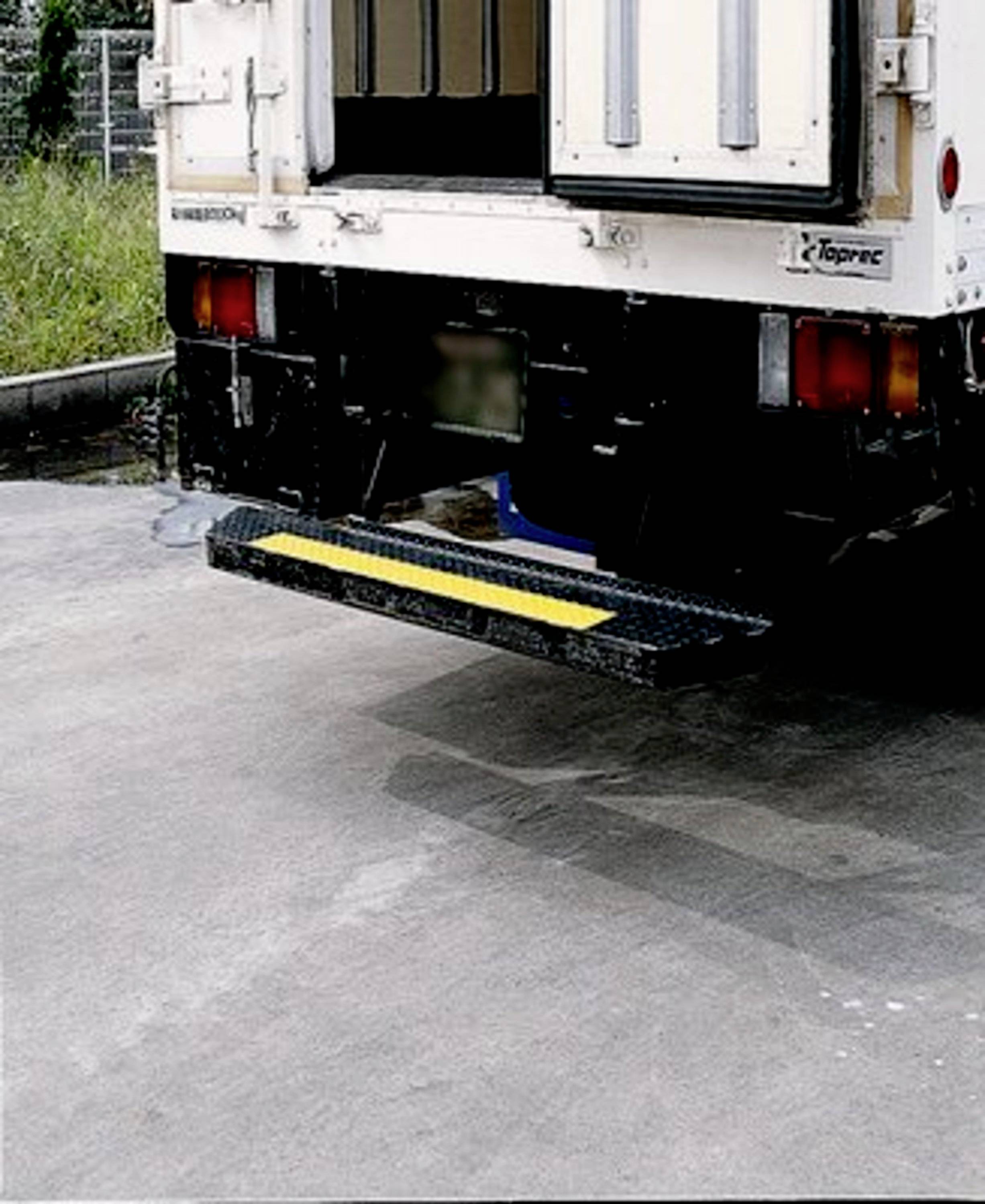 Rückansicht eines LKW mit geöffneter Tür und heruntergelassener Einstiegsstufe auf einem Industriegelände.