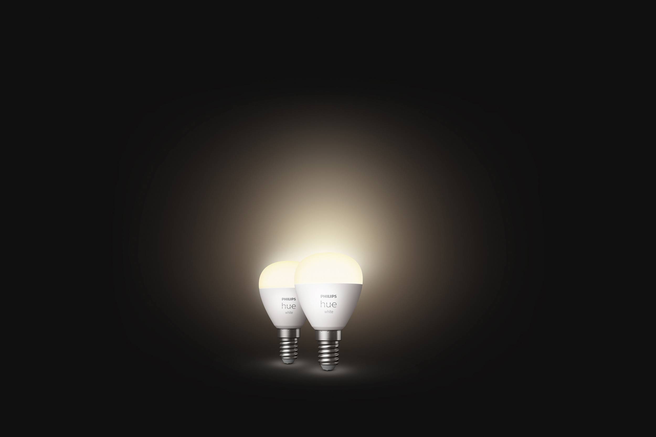 Zwei leuchtende Glühbirnen auf dunklem Hintergrund, die warmes Licht ausstrahlen.
