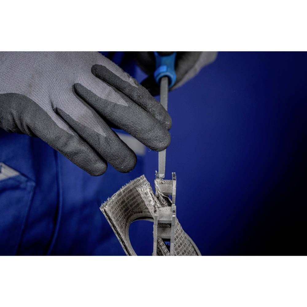 Person trägt Handschuhe, verwendet Werkzeug auf einem Metallstück in blauer Umgebung. Fokussiert auf präzise Handarbeit.