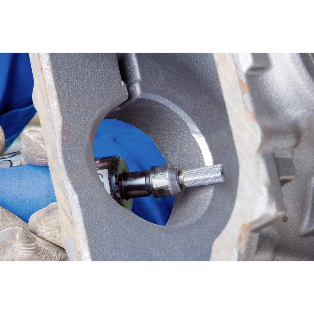 Ein Handwerker schleift mit einem rotierenden Werkzeug eine Metallfläche in einer Werkstatt. Der Fokus liegt auf präziser Bearbeitung.