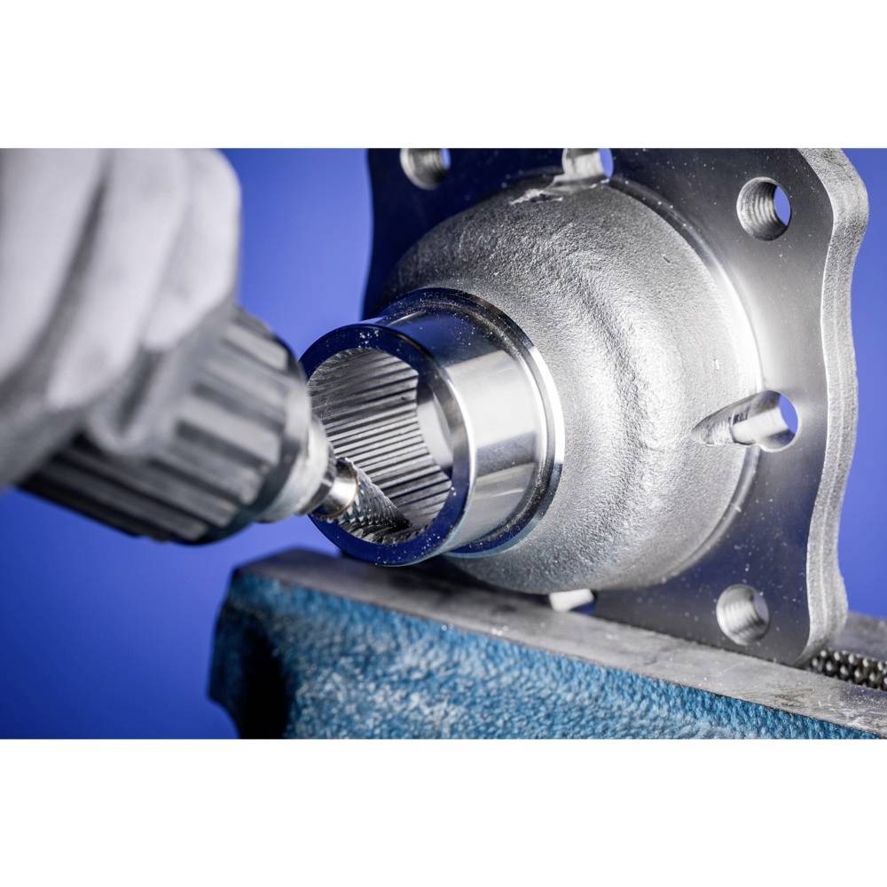 Eine Nahaufnahme eines Winkelschleifers, der an einem metallischen Autoteil arbeitet, vor einem blauen Hintergrund.