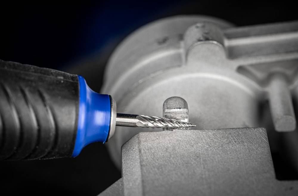 Ein Fräser bearbeitet ein Metallwerkstück. Eine Nahaufnahme zeigt den Fräser in Aktion, Metallspäne entstehen an der Kontaktstelle.