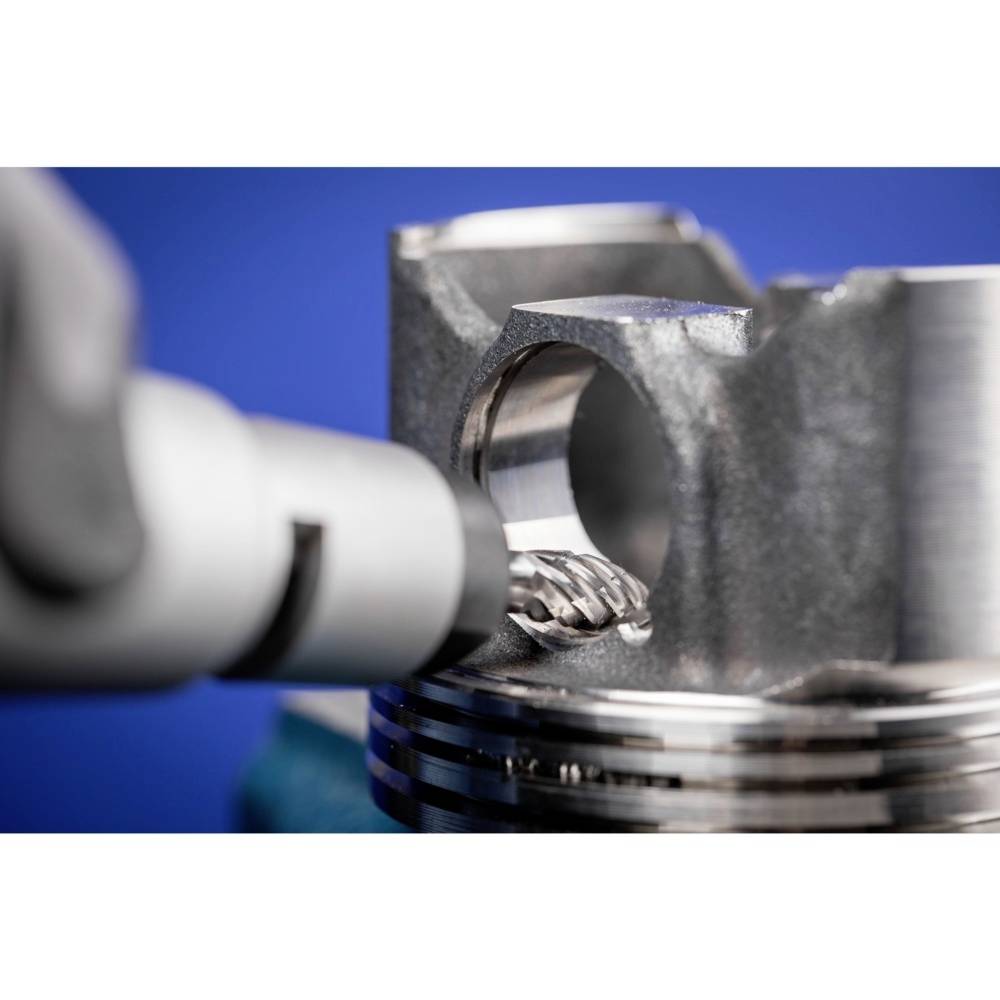 Ein Bohrer bearbeitet ein metallisches Werkstück. Nahaufnahme zeigt den Kontaktpunkt, während Metallspäne entstehen.