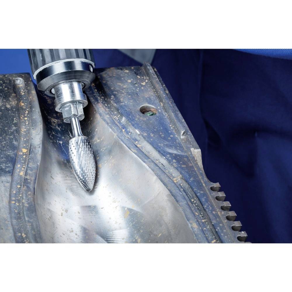 Nahaufnahme einer Maschine, die mit einem rotierenden Werkzeug auf einer Metalloberfläche arbeitet. Die Umgebung wirkt industriell.