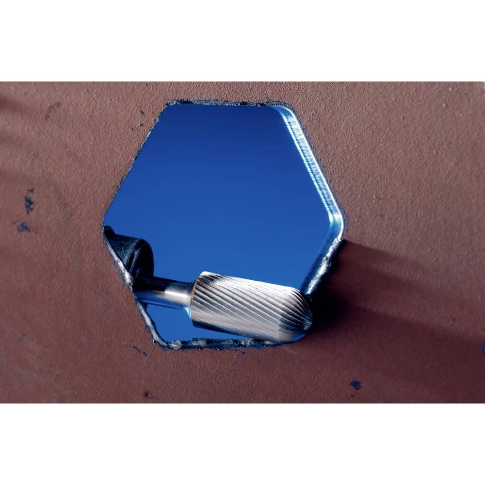 Ein sechseckiges Loch in einer Metallfläche, durch das ein rotierender Schleifer ragt, vor blauem Hintergrund.