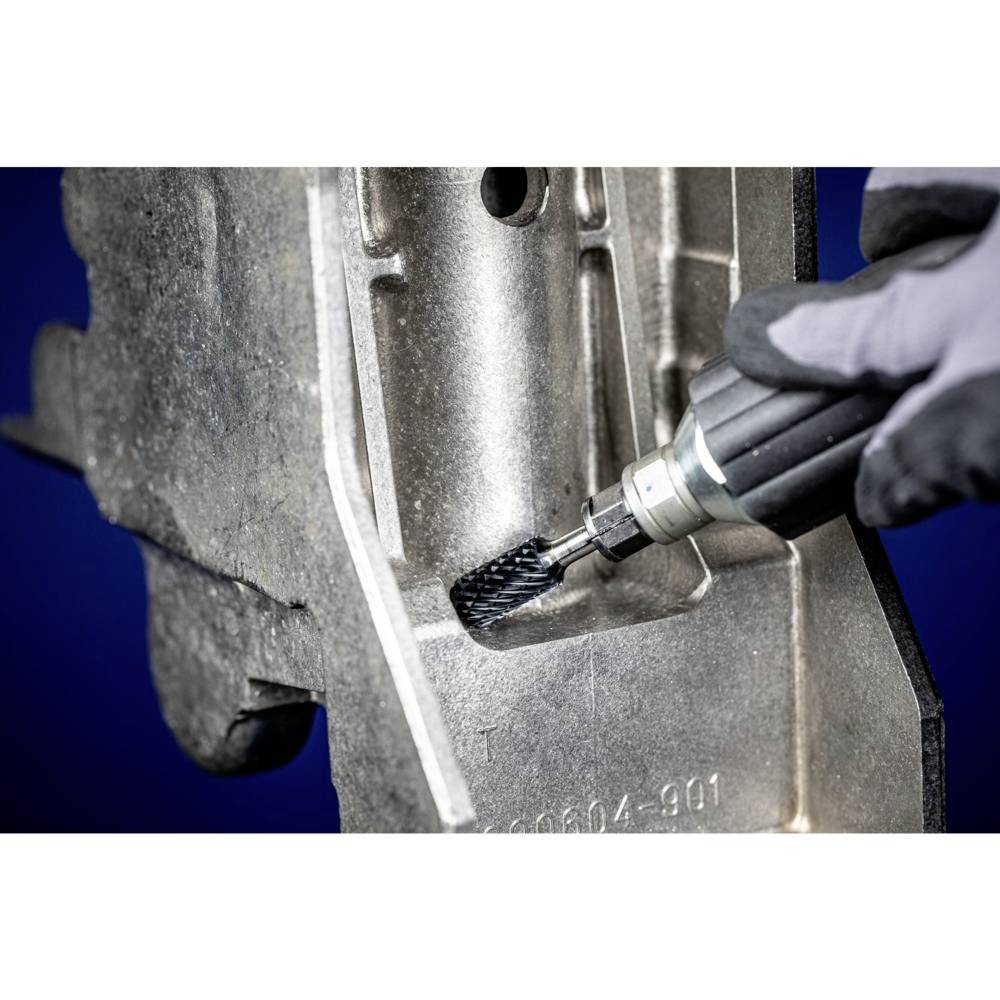 Eine Person verwendet ein rotierendes Werkzeug, um eine Metalloberfläche zu bearbeiten. Sie trägt hierbei einen grauen Handschuh.