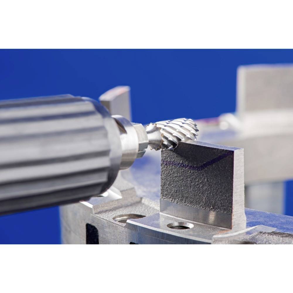 Ein rotierendes Schleifwerkzeug bearbeitet die Oberfläche eines Metallblocks. Das Bild zeigt Nahaufnahme einer industriellen Bearbeitung.