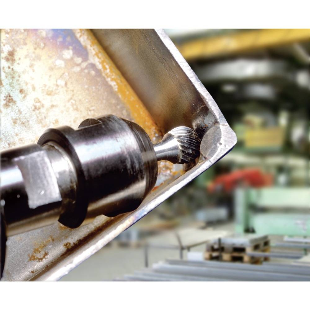 Industriebohrmaschine bearbeitet Metallplatte in Werkstatt. Präzisionsbohrer an Ecke der Platte, unscharfer Hintergrund mit Werkzeugen.