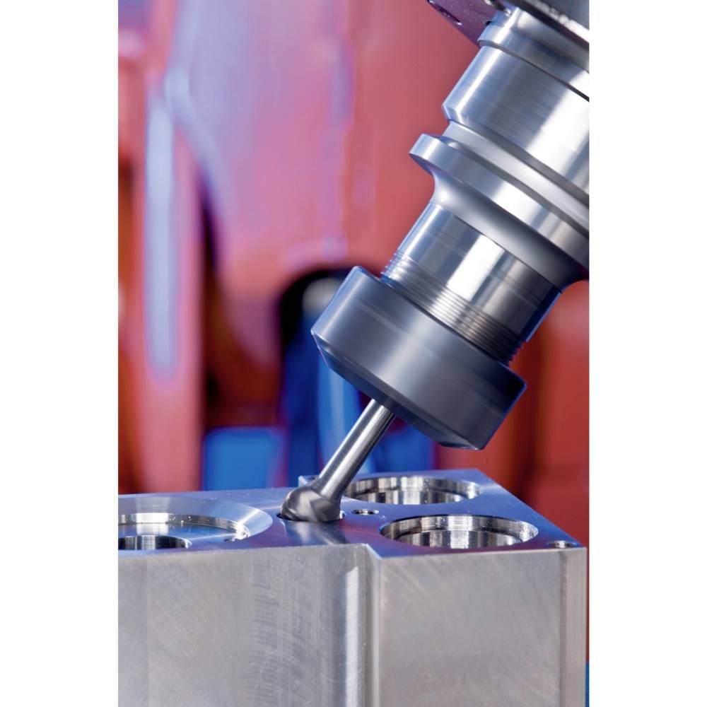 Fräswerkzeug bearbeitet Metallblock in Fabrikumgebung. Hauptaugenmerk liegt auf präziser Bearbeitung mit rotierendem Fräskopf.