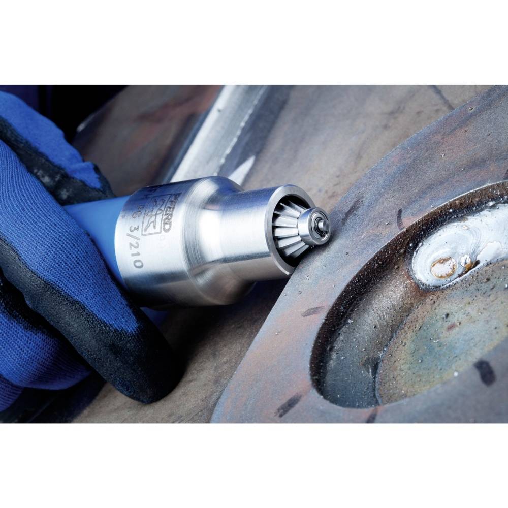 Eine Person in blauen Arbeitshandschuhen verwendet ein Druckluftwerkzeug, um Metall zu schleifen. Das Werkzeug ist nah an einer rostigen Oberfläche.