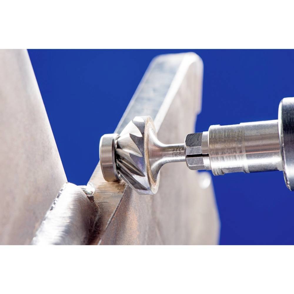 Ein Metallbohrer mit gezacktem Kopf bearbeitet eine Metallfläche. Nahaufnahme zeigt präzisen Arbeitsvorgang.