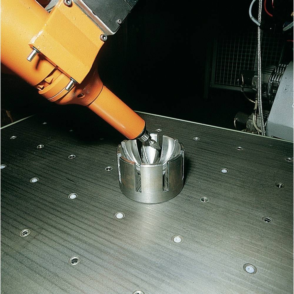 Industrieroboter bearbeitet Metallwerkstück auf gestanztem Tisch. Genauigkeit in der Fertigung.