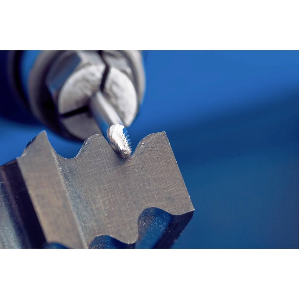 Nahaufnahme einer Fräsmaschine, die ein Metallstück bearbeitet. Das Metall hat gezackte Kanten, der Hintergrund ist unscharf in Blau.