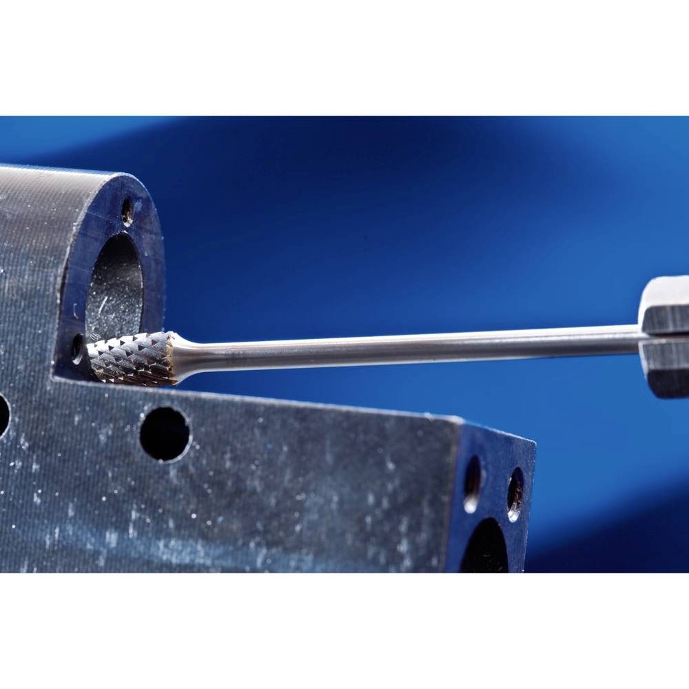 Ein Metallbohrer bearbeitet ein rundes Werkstück vor einem blauen Hintergrund.