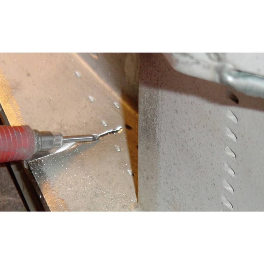 Nahaufnahme eines Bohrers, der ein kleines Loch in ein Metallblech bohrt, umgeben von Metallspänen.