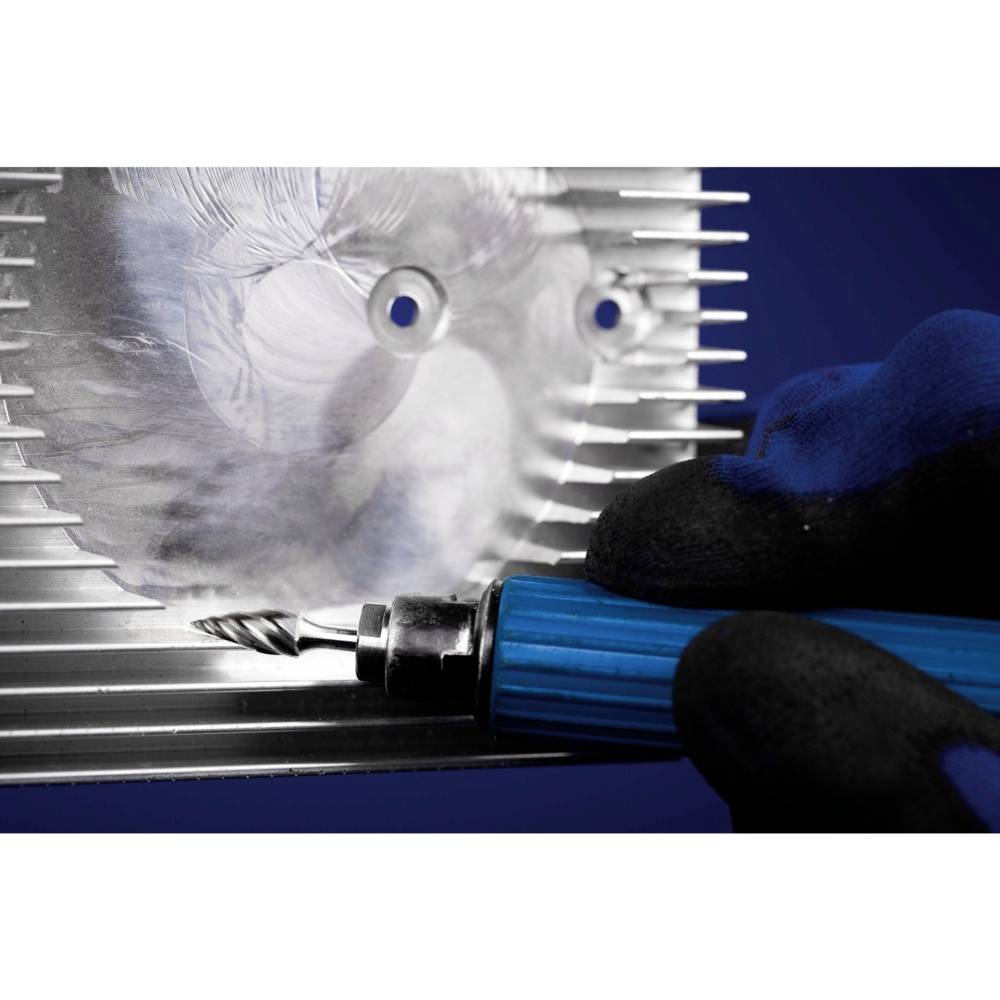 Eine Person trägt einen Handschuh und hält ein blaues Werkzeug an ein metallisches Objekt mit Struktur und Reflexionen.