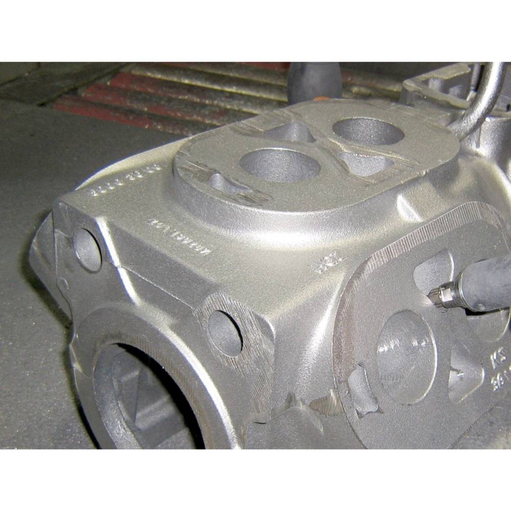 Industrie-Bauteil mit zwei runden Vertiefungen und Anschlusslöchern, vermutlich ein Teil eines Motors oder Maschinenbaus.