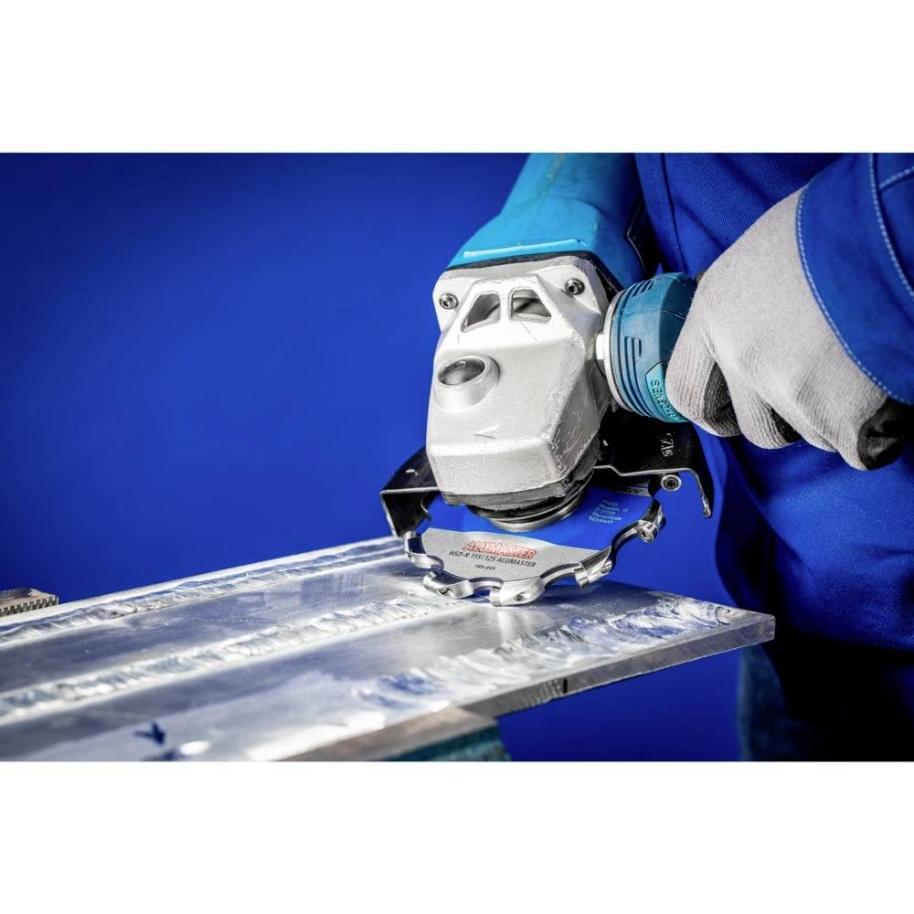 Eine Person benutzt einen Winkelschleifer, um Metall zu schneiden. Die Person trägt blaue Arbeitskleidung und Schutzhandschuhe.