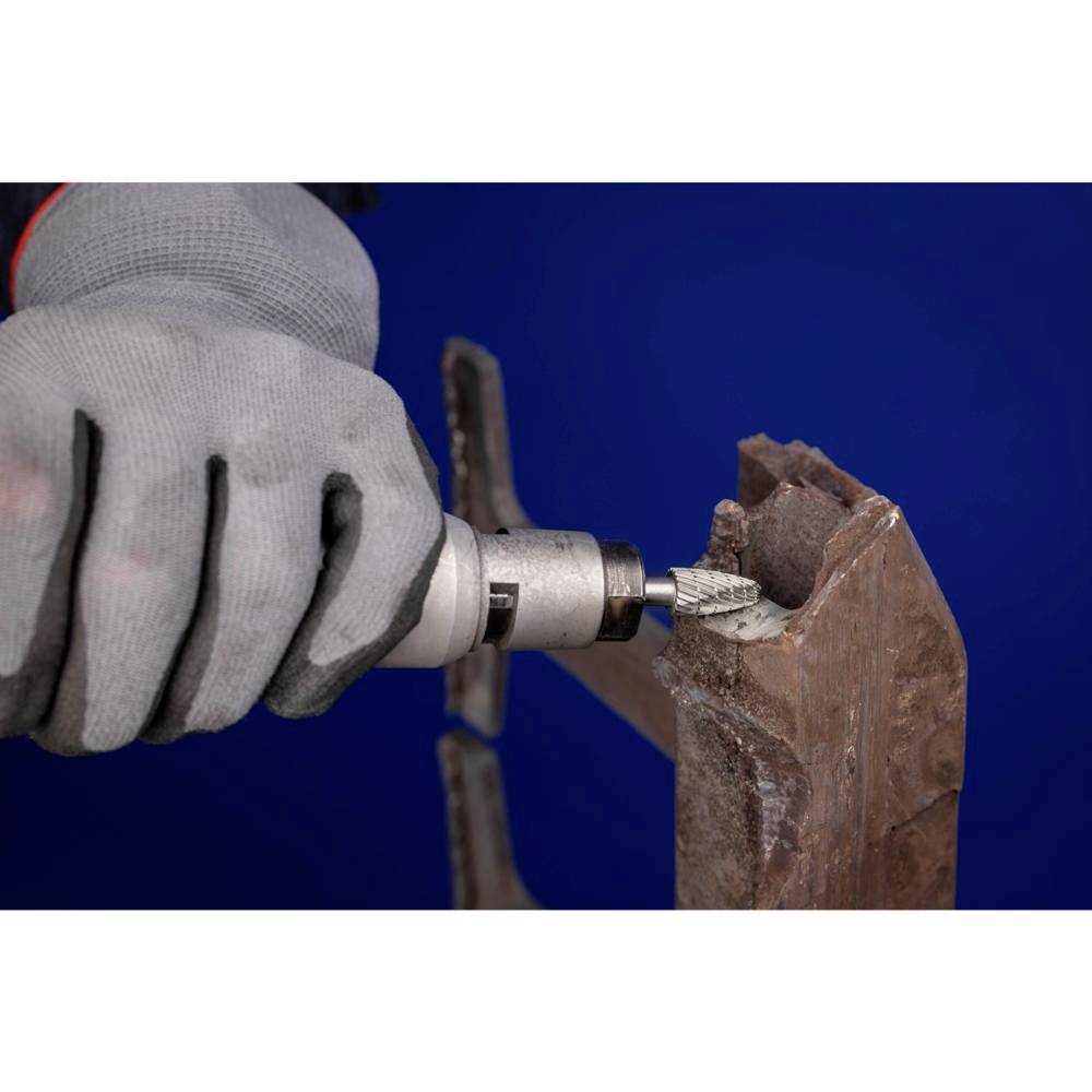 Eine Person trägt einen grauen Handschuh und schleift mit einem Schleifgerät Metall auf einem rostigen Winkelstück.