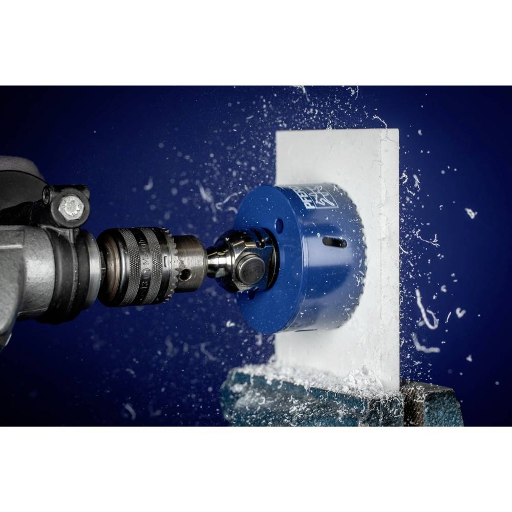 Ein blauer Bohrkopf schneidet in eine weiße Oberfläche, während Wasser spritzt. Eine industrielle Bohrsituation.