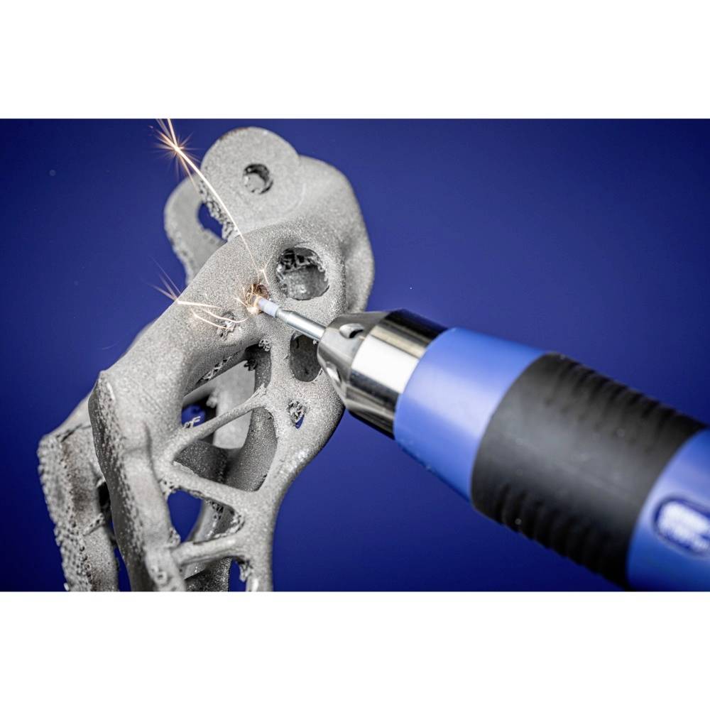 Ein 3D-gedruckter Metallgegenstand wird mit einem blauen Handwerkzeug bearbeitet, Funken fliegen. Hintergrund in Blau.
