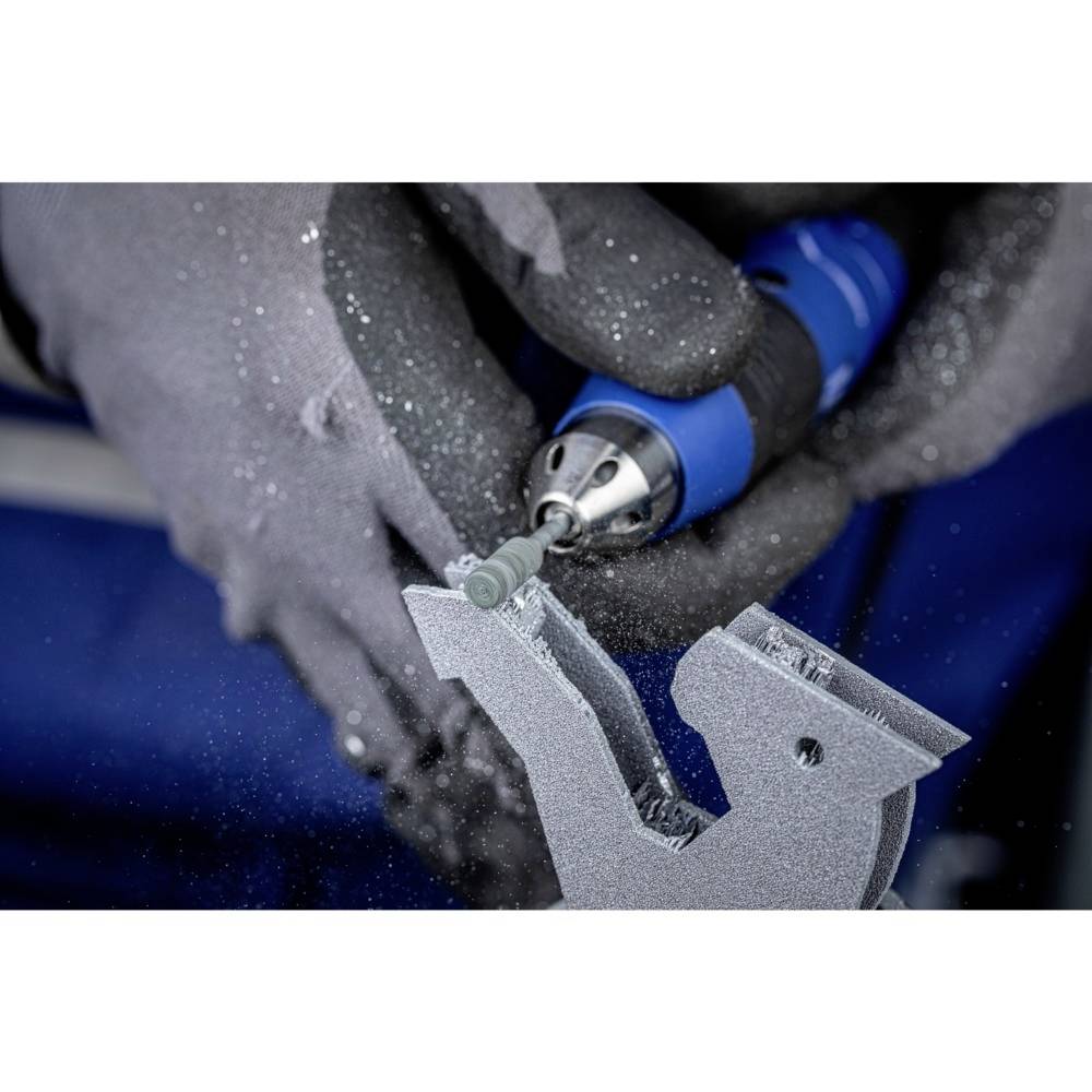 Nahaufnahme einer Person, die mit einem blauen Drehwerkzeug Metall bearbeitet. Funken und Metallspäne fliegen von einem Bearbeitungsstück weg.