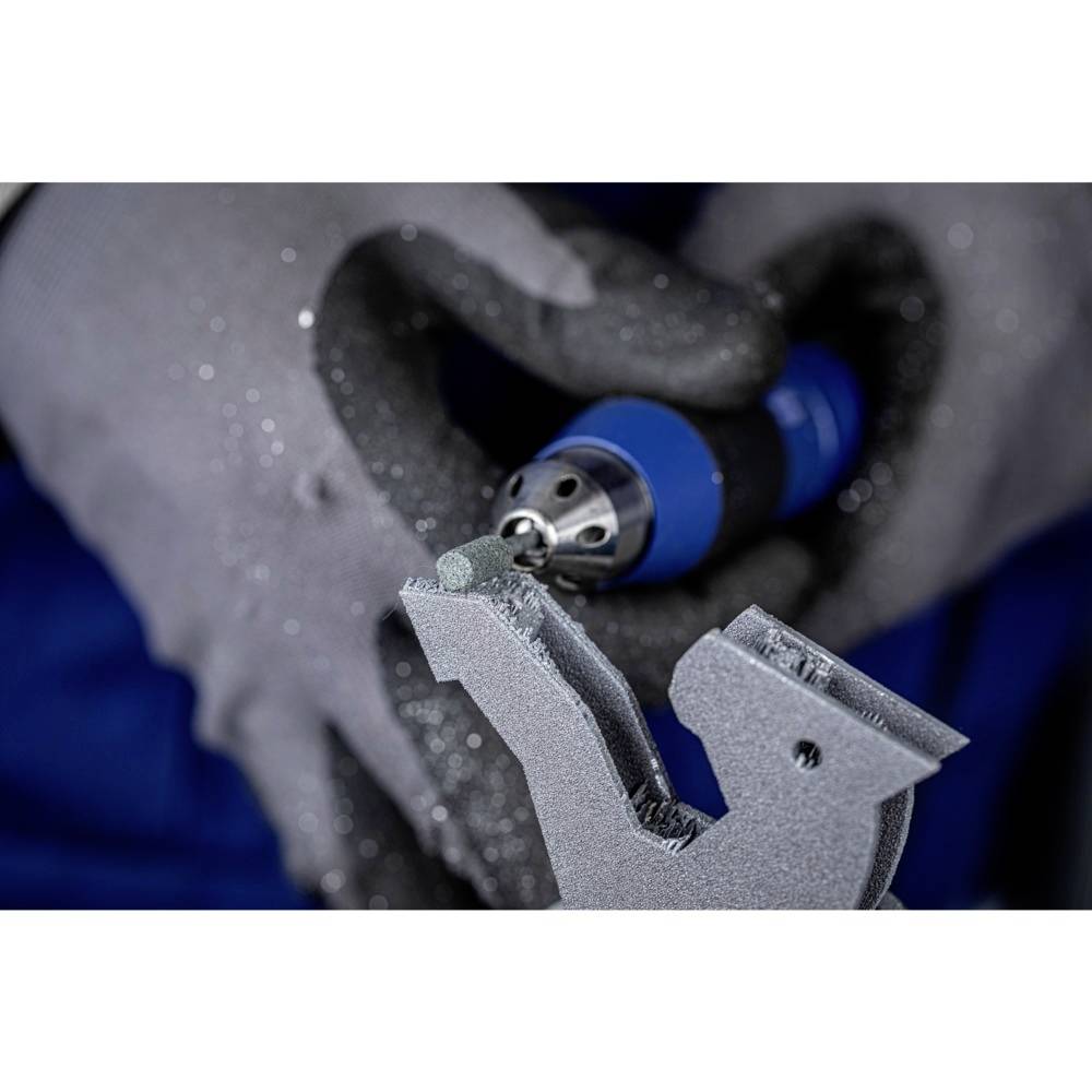 Handwerker mit grauen Handschuhen hält eine blaue, elektrische Schleifmaschine und bearbeitet ein graues Metallteil.