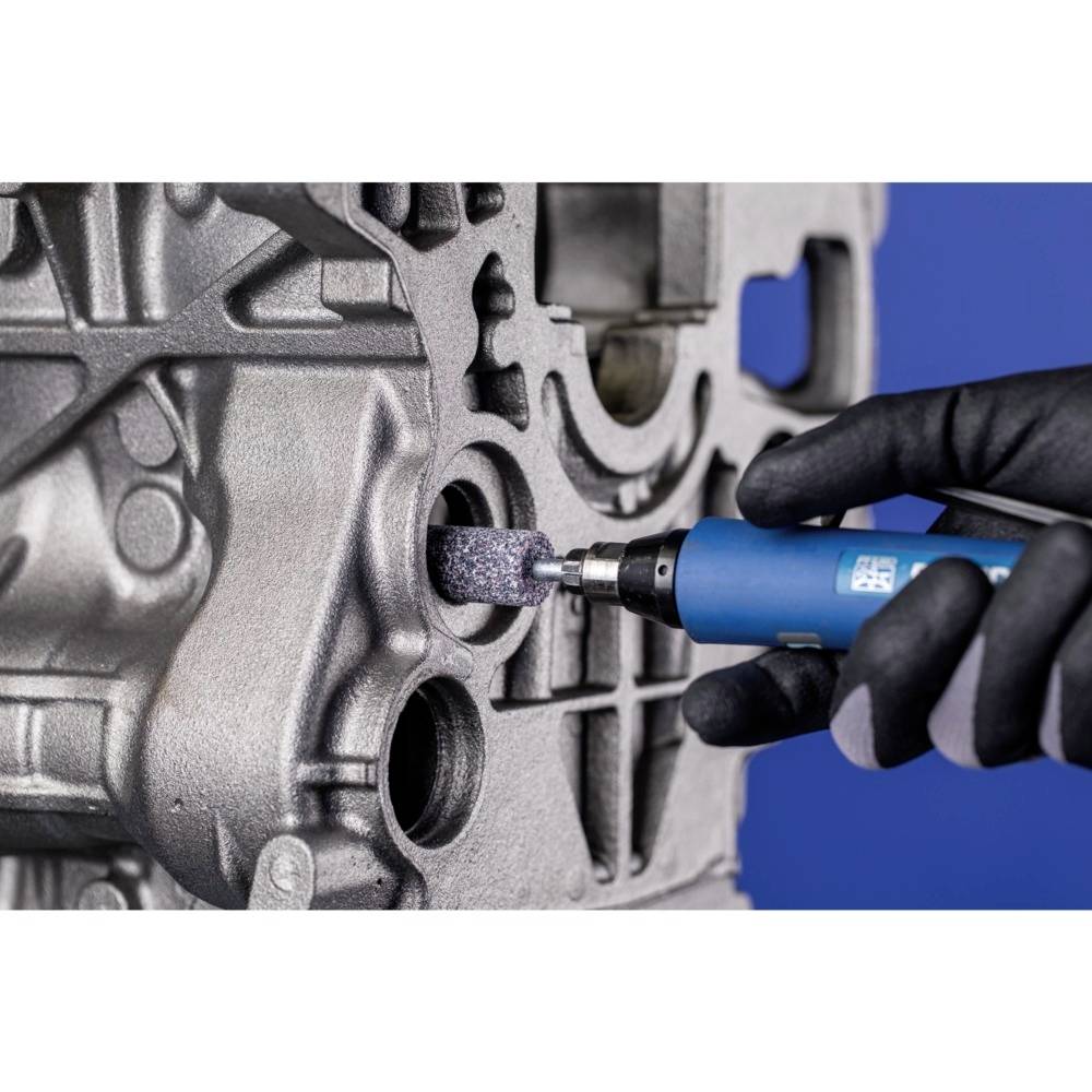 Eine Person bearbeitet ein Metallteil mit einem blauen Schleifgerät. Fokus auf Präzision und Werkstoffbearbeitung.