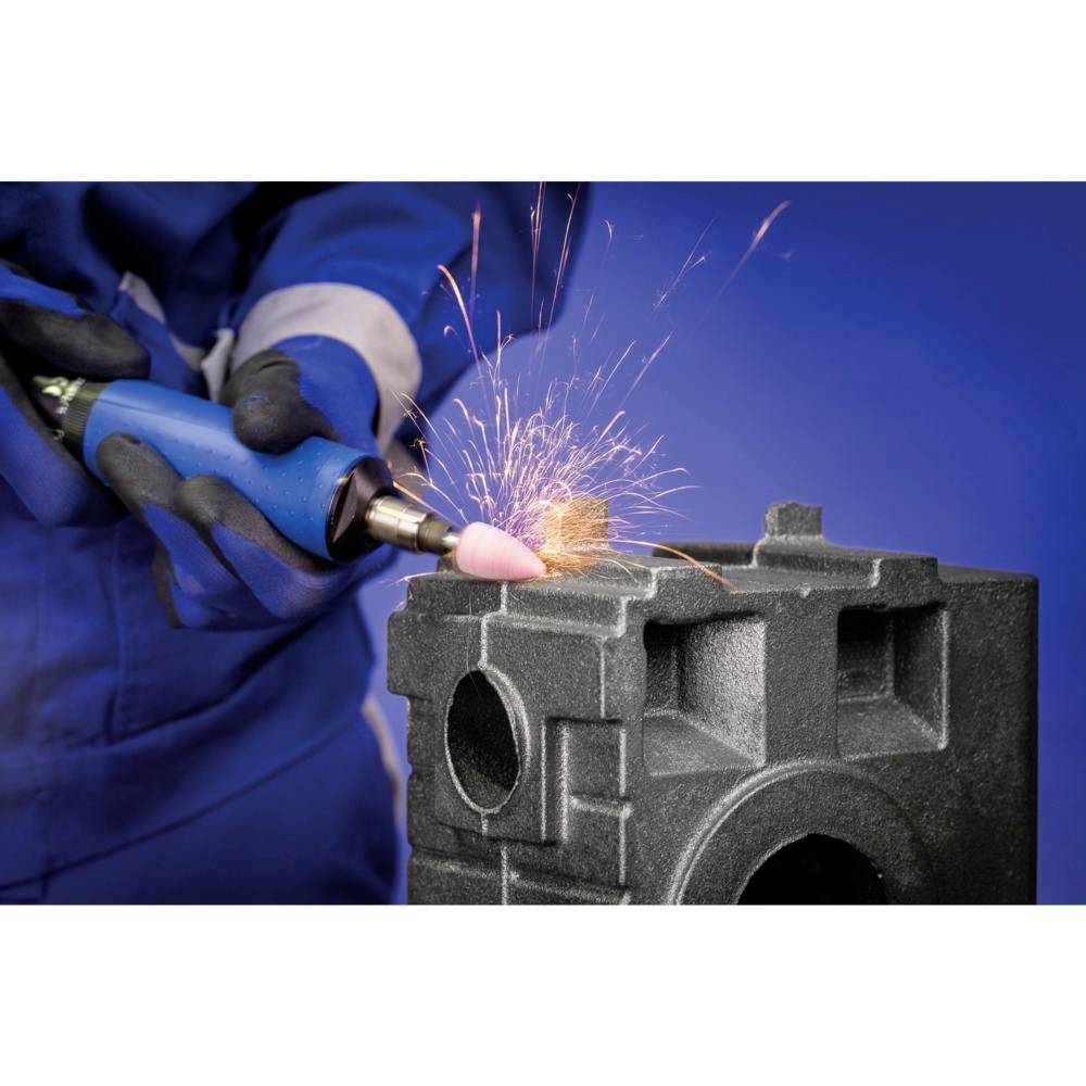 Hand mit blauem Schutzanzug schleift schwarzes Metallblock, Funken sprühen. Industriearbeit in heller Umgebung.
