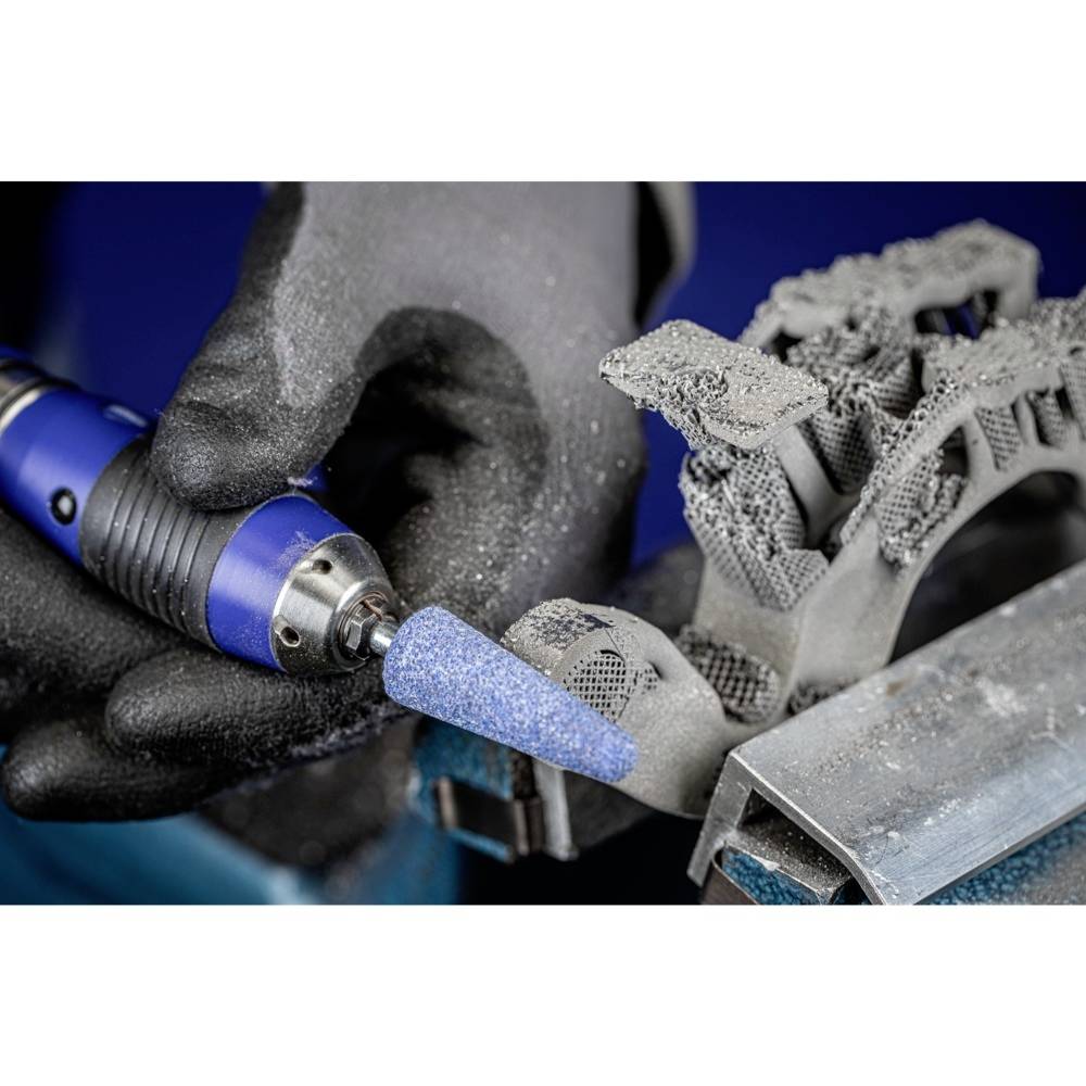 Eine Person trägt schwarze Handschuhe und benutzt ein blaues, elektrisches Werkzeug, um Metall zu bearbeiten. Metalldetails sichtbar.