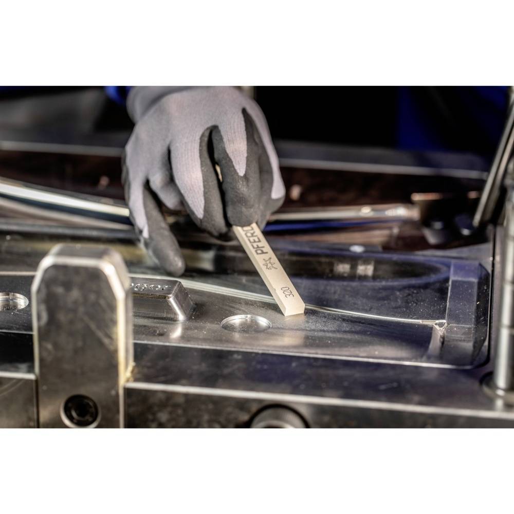 Eine behandschuhte Person benutzt ein Messgerät, um Metallteile zu messen. Fokus liegt auf Präzision und Handhabung des Werkzeugs.