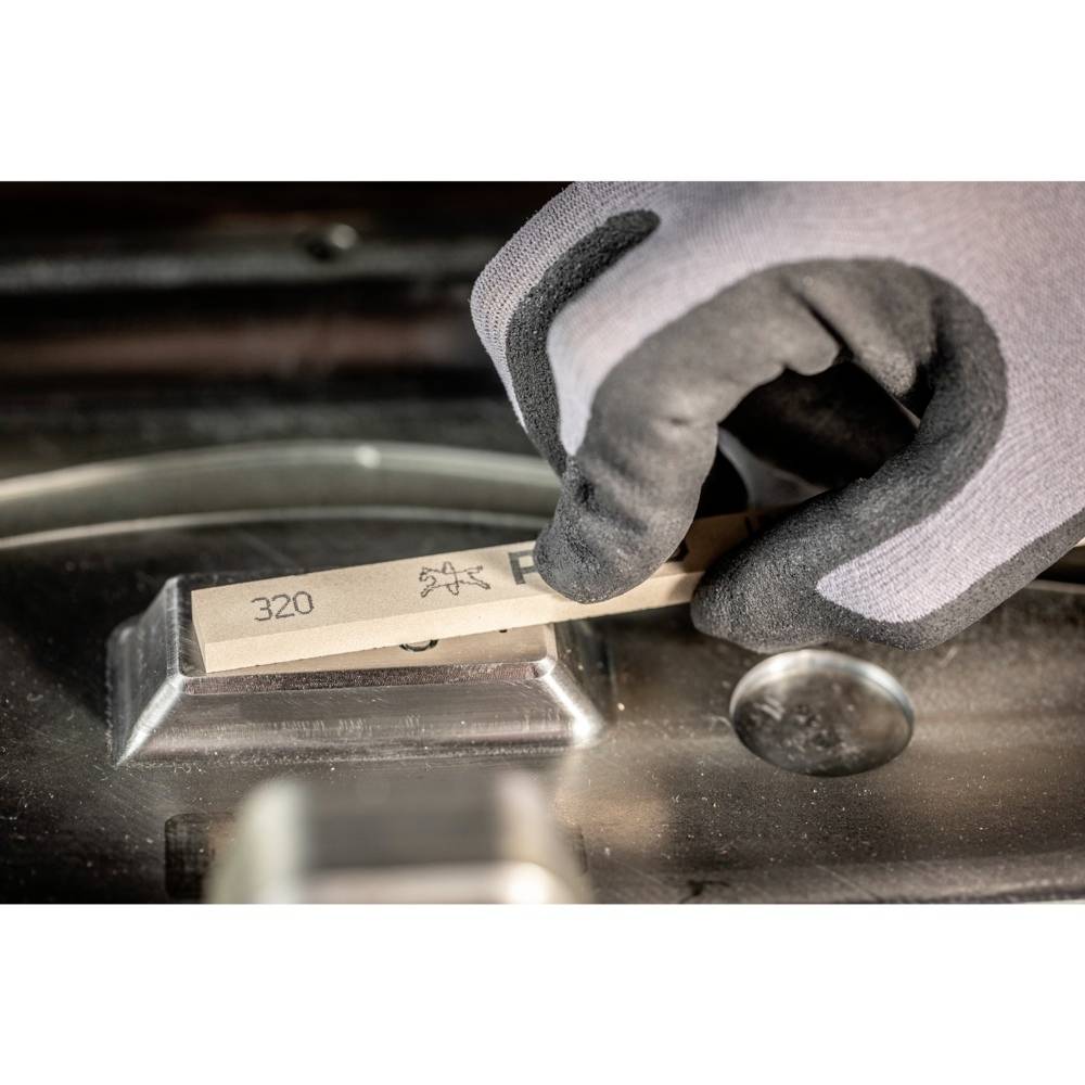 Eine behandschuhte Hand hält ein Schleifpapier mit der Körnung 320. Das Schleifpapier wird über eine metallische Oberfläche geführt.