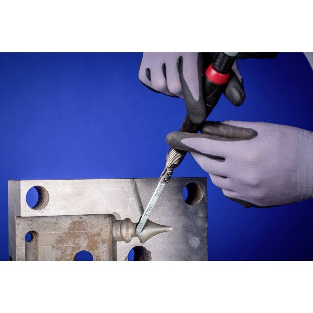 Eine Person trägt Handschuhe und benutzt ein Elektrowerkzeug, um ein Metallteil auf einer blauen Hintergrundfläche zu bearbeiten.
