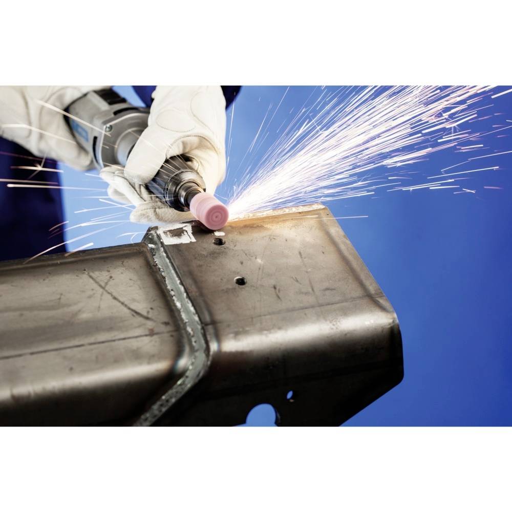 Eine Person mit Handschuhen schleift Metall mit einem Winkelschleifer. Es fliegen Funken, blauer Hintergrund.