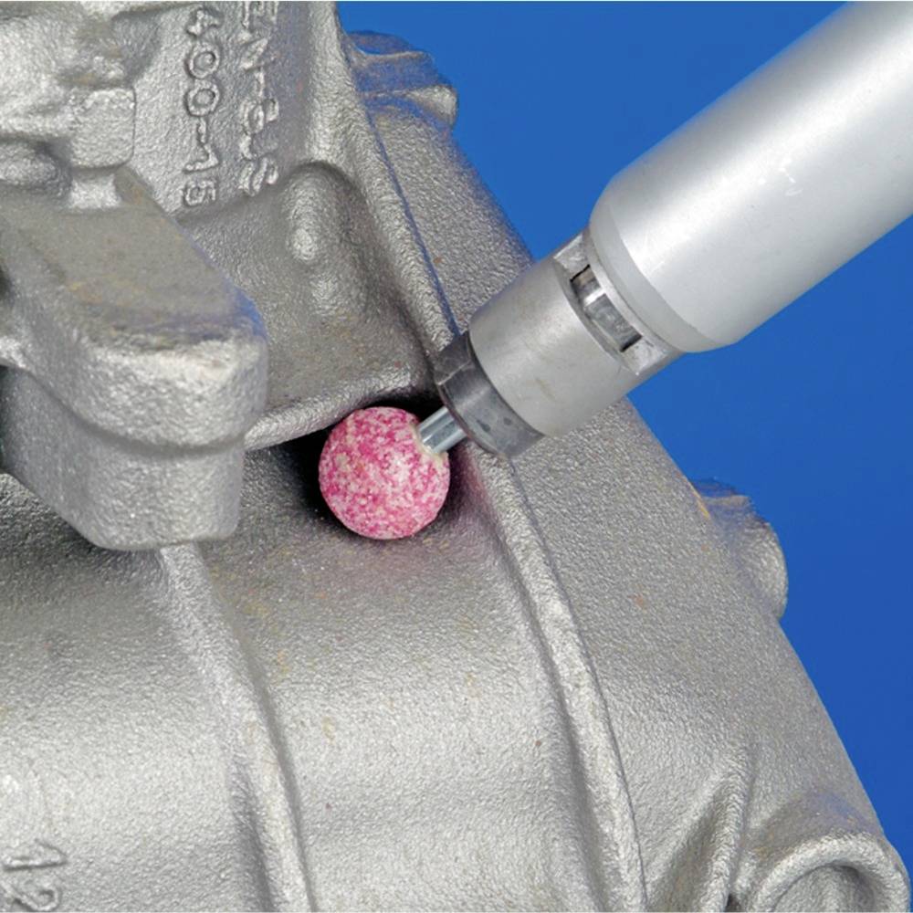 Eine rotierende Schleifmaschine bearbeitet eine Metalloberfläche. Eine rosa Schleifscheibe poliert oder schleift das Material.