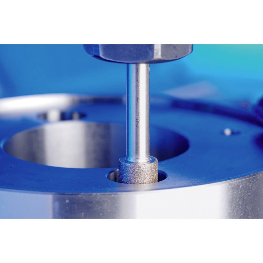 Ein Metallwerkzeug bearbeitet präzise eine Oberfläche auf einer industriellen Maschine, umgeben von blauer Ausrüstung.