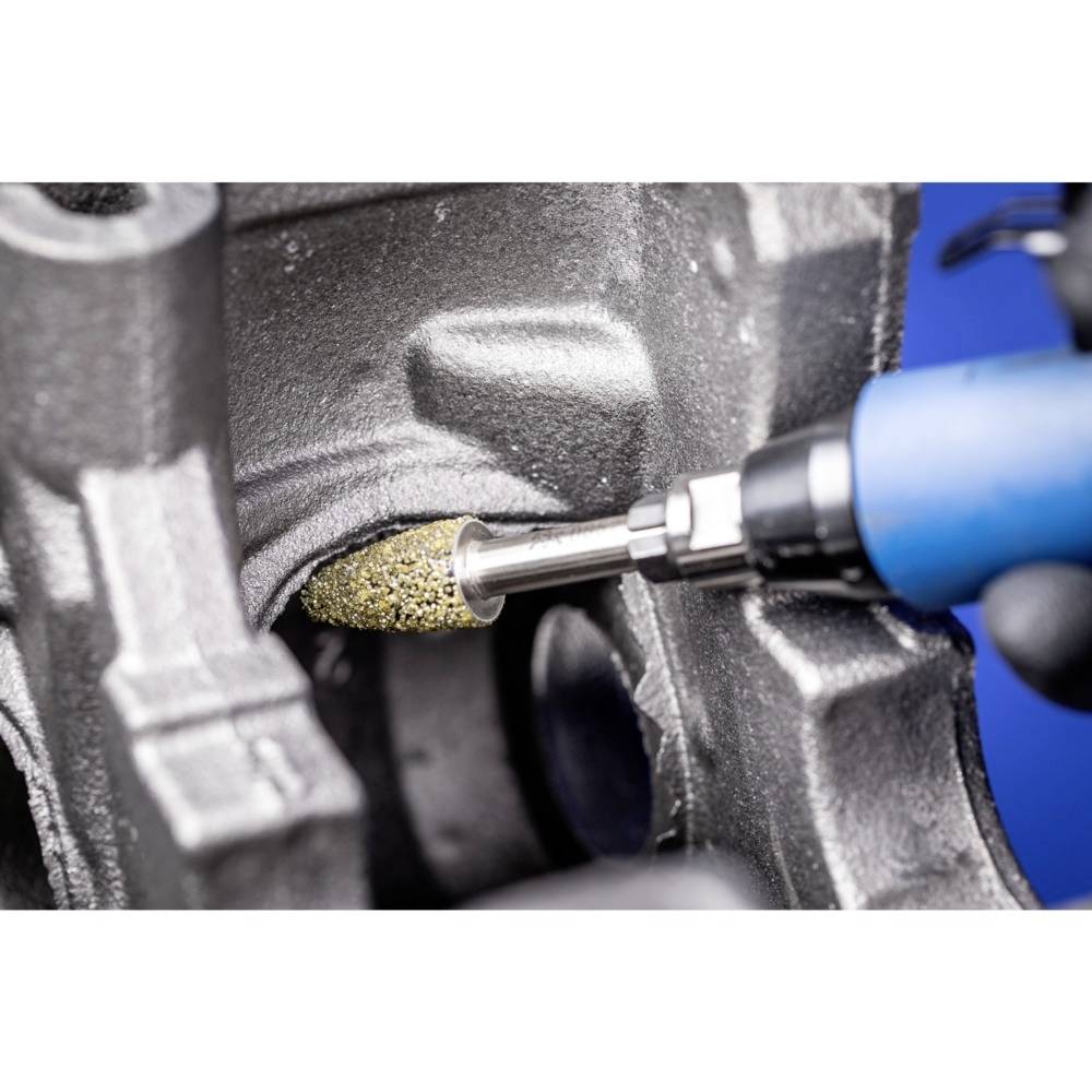 Eine blaue Schleifmaschine bearbeitet eine Metalloberfläche, entfernt unebene Stellen. Das Bild zeigt Detailarbeit an einer Maschine.