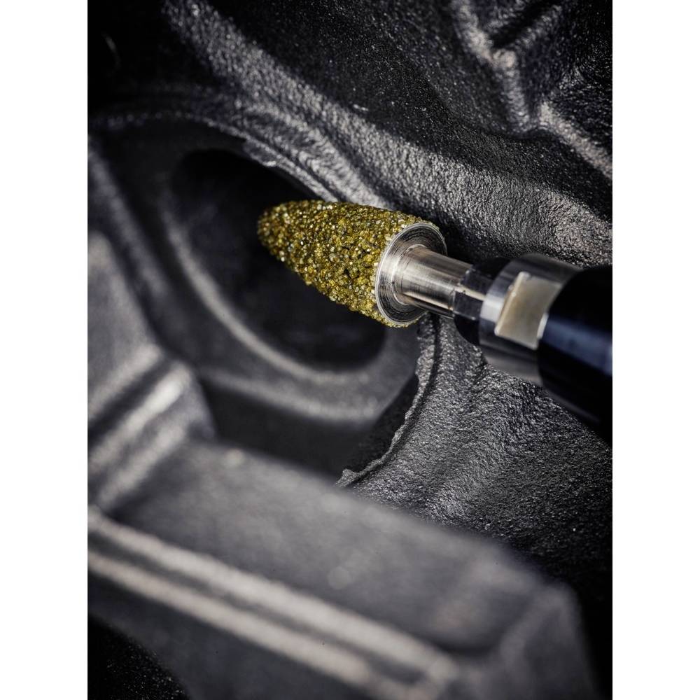 Blick auf ein rotierendes Schleifwerkzeug bei der Metallbearbeitung. Das Werkzeug hat eine goldene Schleiffläche und bearbeitet eine schwarze Metalloberfläche.