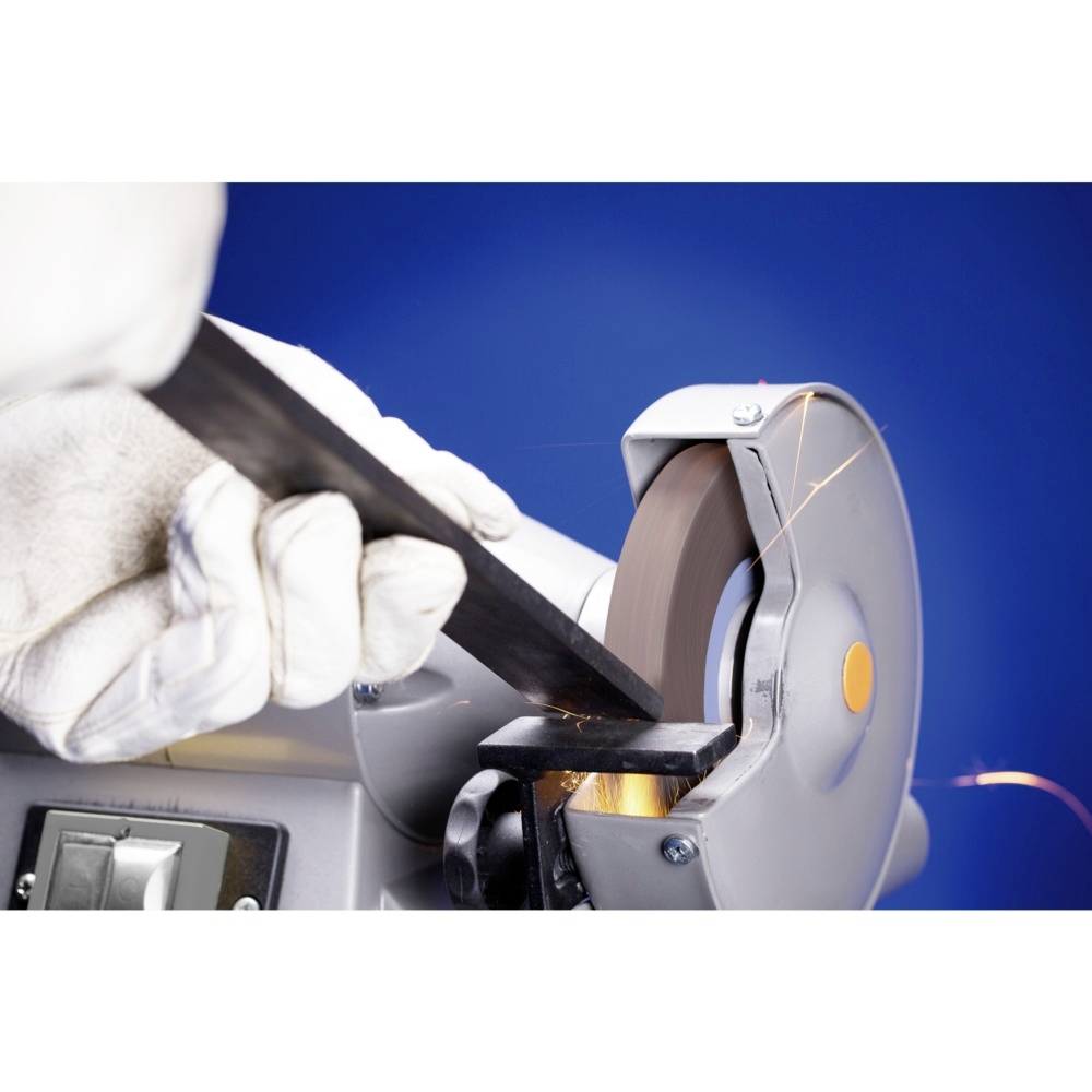 Eine behandschuhte Hand hält ein Metallstück an einen rotierenden Schleifstein, Funken fliegen auf blauem Hintergrund.