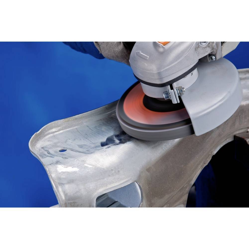 Eine Schleifmaschine bearbeitet eine Metalloberfläche. Funken fliegen, da Material abgetragen wird, in einem industriellen Kontext.