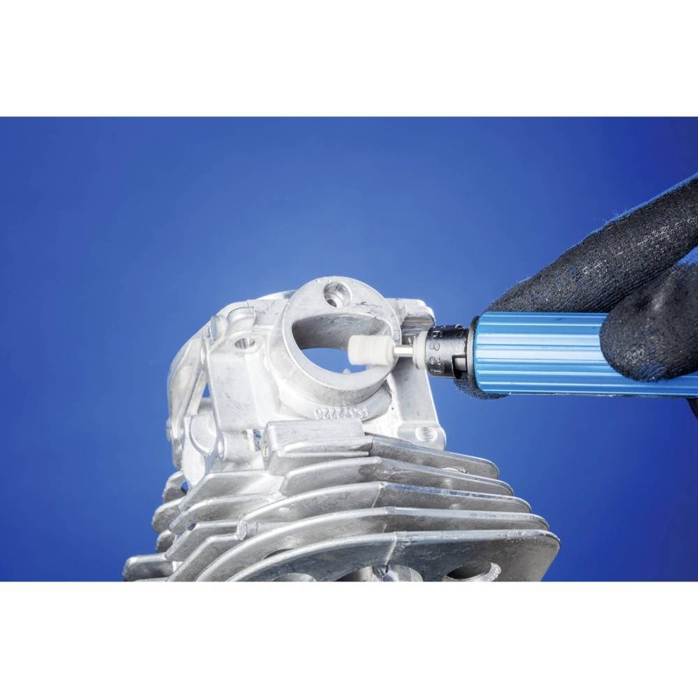 Eine Person bearbeitet einen Metallmotorblock mit einem blauen Schleifwerkzeug, auf blauem Hintergrund.