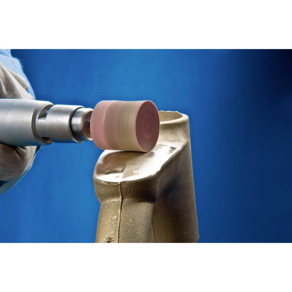 Ein Handwerker schleift die Oberfläche eines Metallteils mit einem Elektrowerkzeug. Der Hintergrund ist blau.