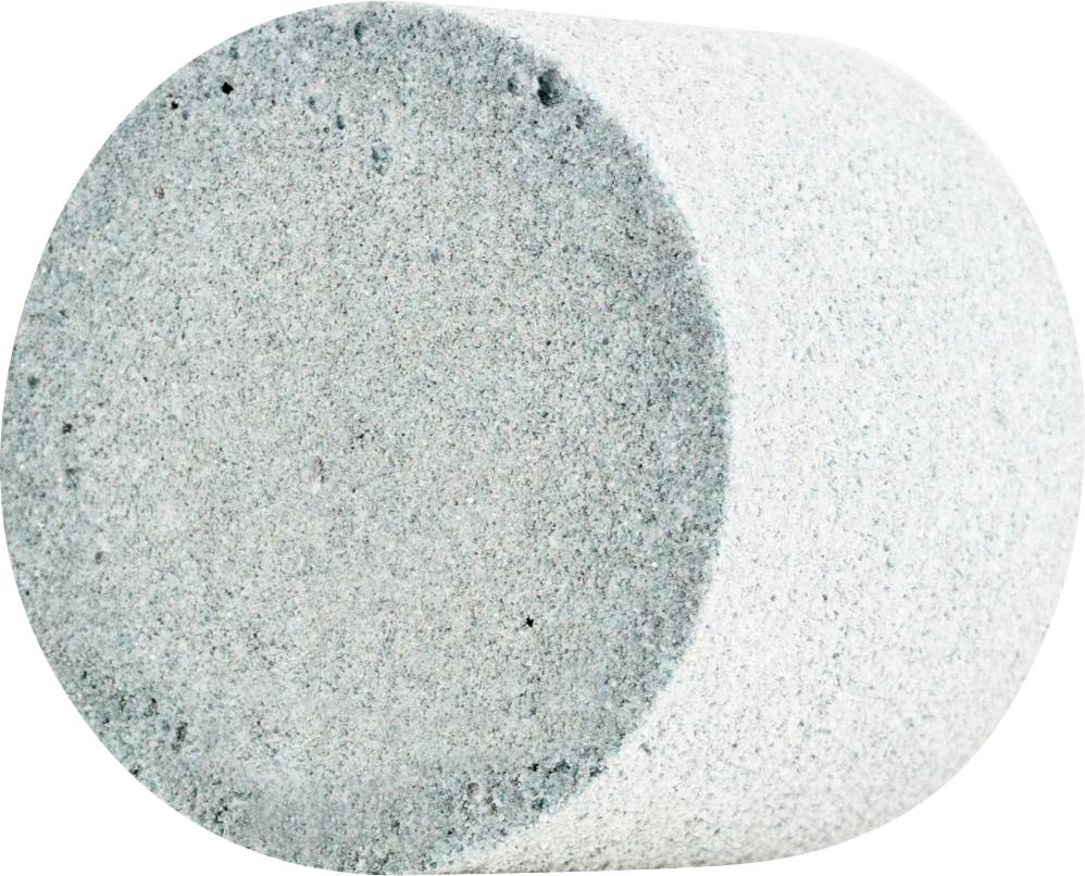 Ein einzelner, zylindrischer Stein in hellem Grau, liegt auf der Seite.